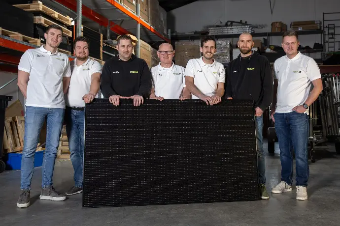 Team van Pebble Zonnepanelen met een zonnepaneel in de loods